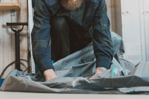 homme réparant une toile de tente Decathlon